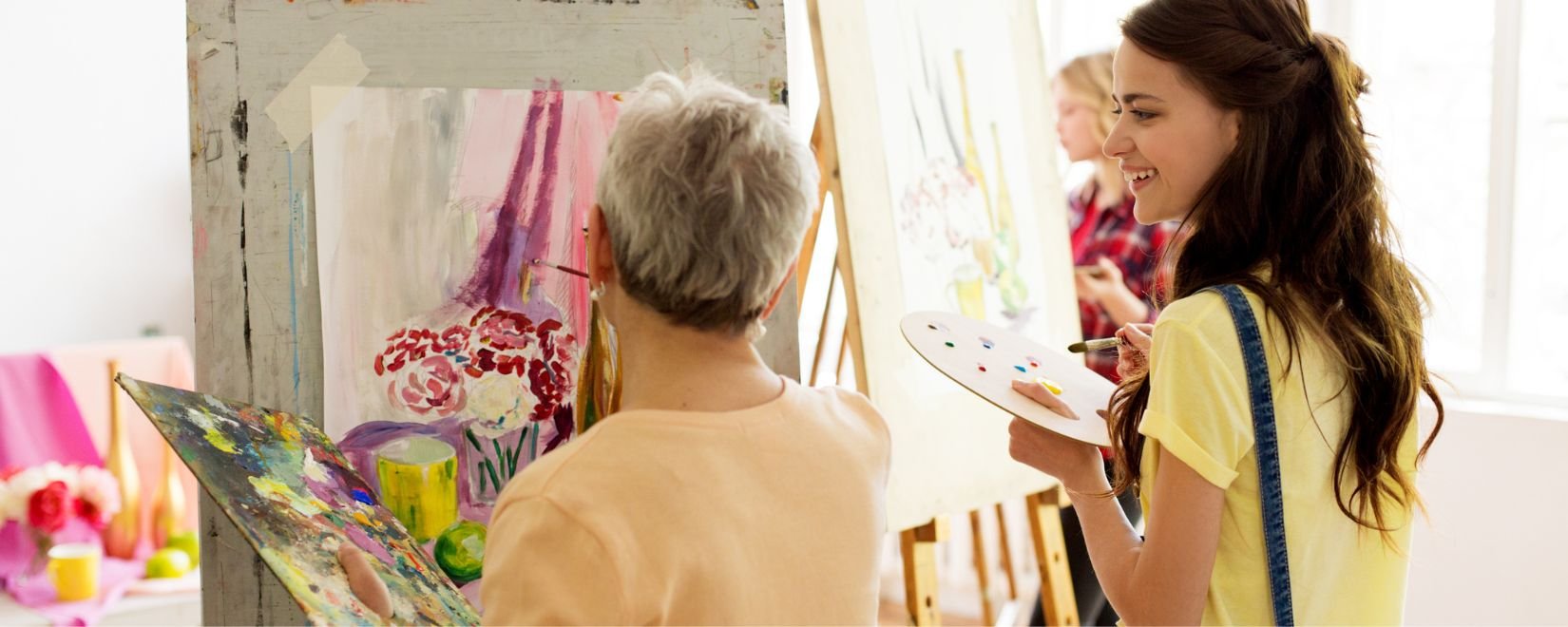 Two women painting large easels 