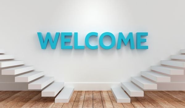 A blue welcome sign on a white wall with two staircases on either side