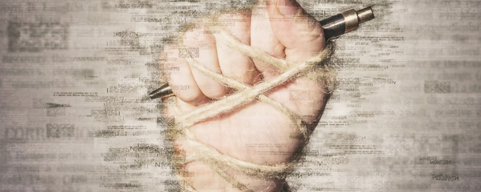A fist wrapped in twine holding a pen against a background of words 