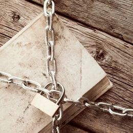 A black and white image of a book under a lock and chain