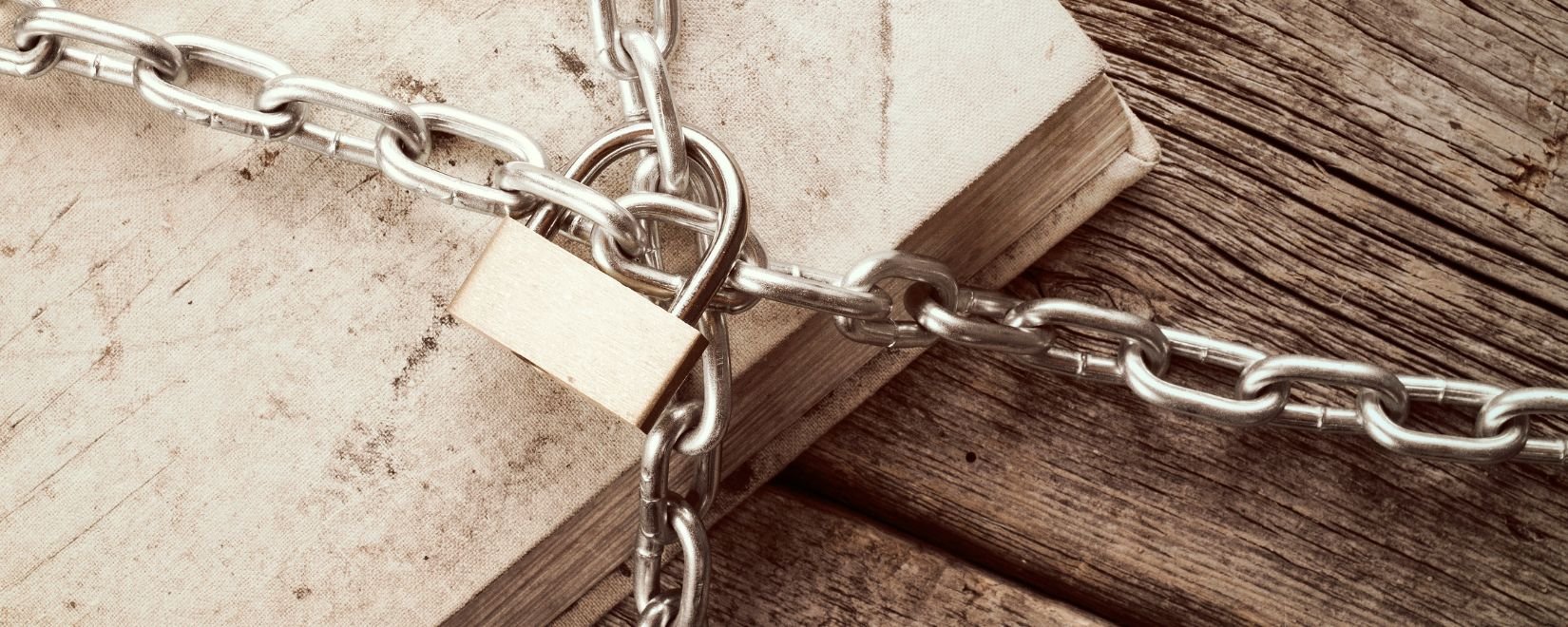 A black and white image of a book underneath a lock and chain