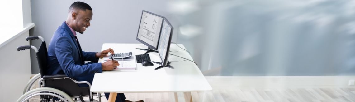 An African-American male employee in a wheelchair working at a computer. 