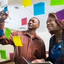 Two African-American employees writing on sticky notes