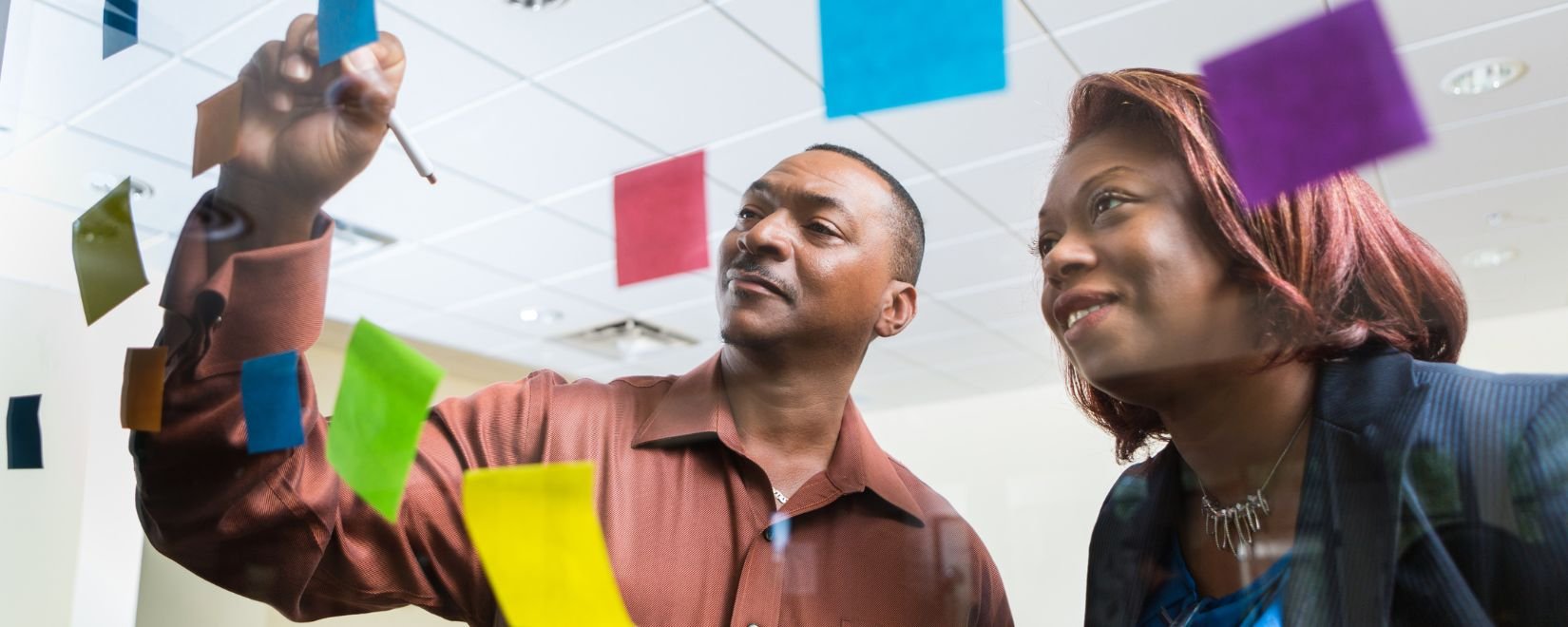 Two African-American employees writing on sticky notes