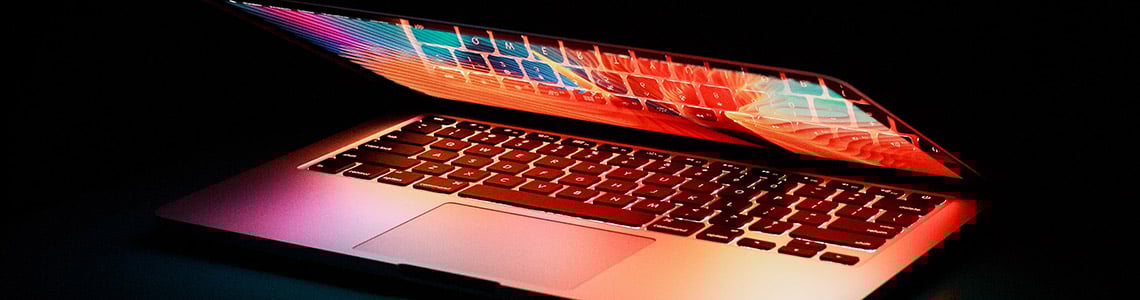 A partially open laptop with a brightly colored screen on a black background