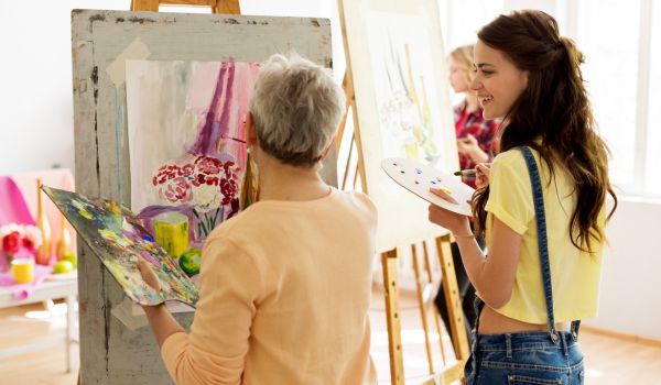 Two women painting on large easels